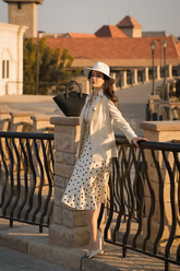 a lady in a beige jacket, a beige vest and a skirt with polka dots
